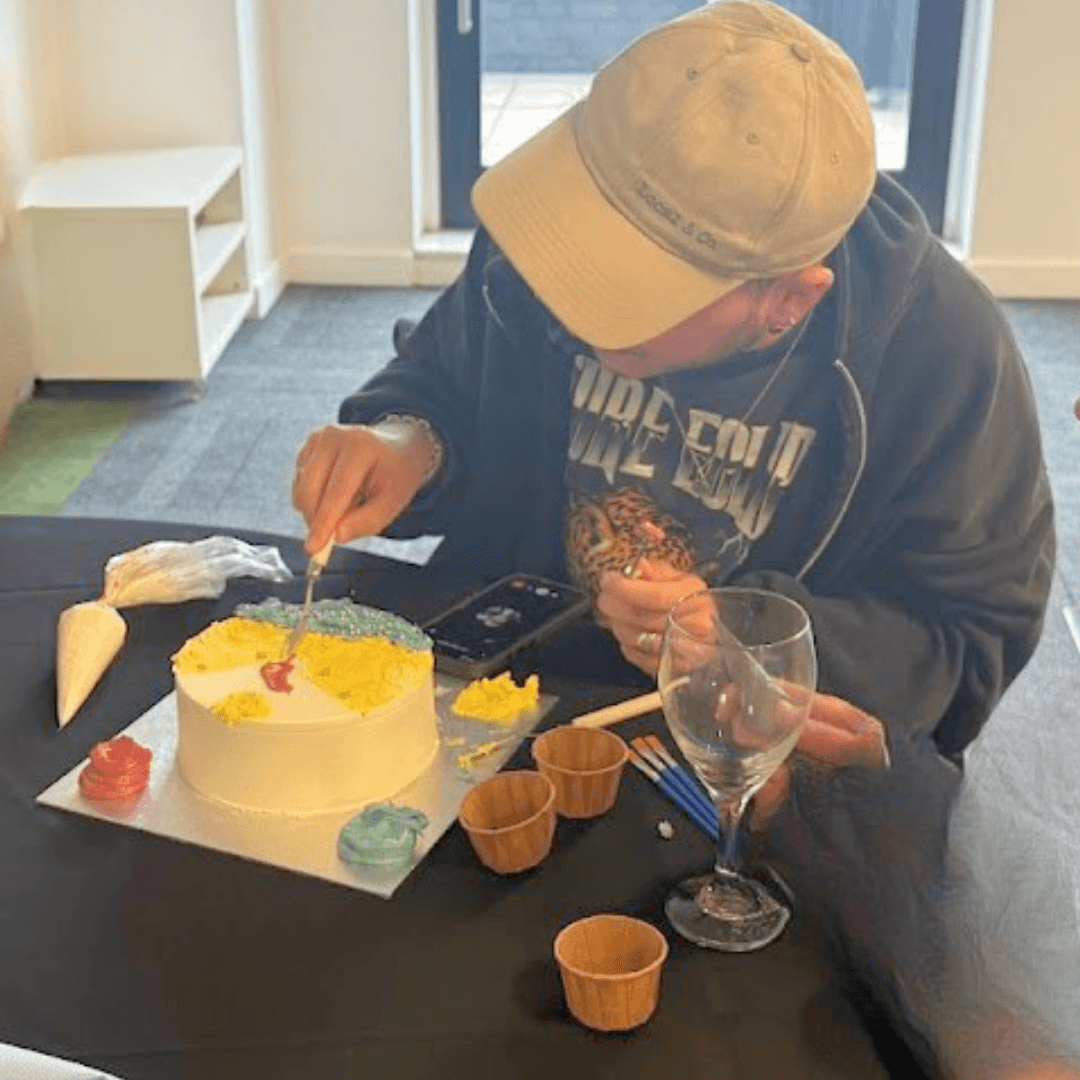 Workshop participant decorating a cake with yellow and blue buttercream